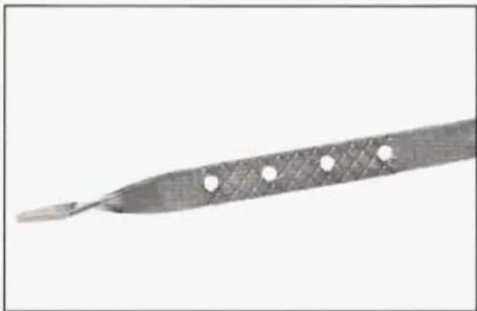 Close-up of a metallic tool with a textured handle and four circular holes, isolated on white background (no text or symbols)