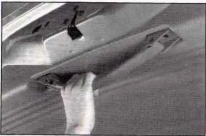Close-up of a hand using a tool to clean or inspect a wooden panel (no visible text or symbols)
