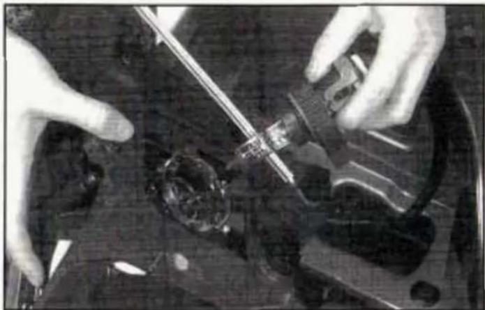 Close-up of hands using a tool to adjust or install electronic components on a circuit board (no visible text or symbols)