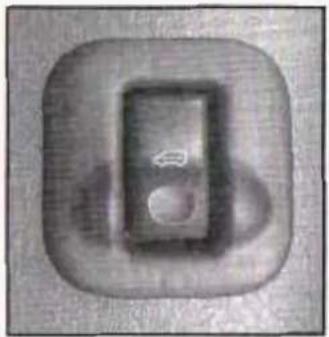 Close-up of a metallic square button with a circular hole and a small leaf symbol (no text or numbers visible)