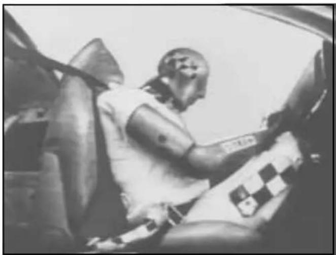 Black-and-white photo of a person seated in a car, wearing a white shirt with a checkered pattern (no visible text or symbols)