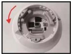 Close-up of a white electronic device interior with a red arrow indicating rotation (no text or symbols visible)