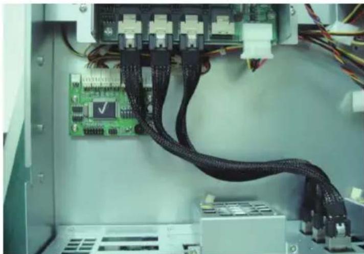 Interior view of an electronic equipment cabinet showing a green circuit board connected to a black cable with multiple ports (no visible text or symbols)