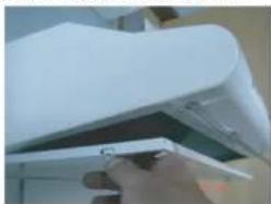 Close-up of a hand holding a white paper airplane with a small attached object (no visible text or symbols)