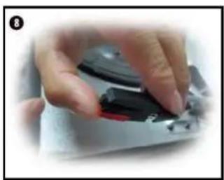 Close-up of a hand holding a black and red device with a circular button, no visible text or symbols