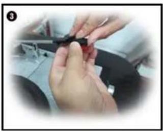 Close-up of hands holding a small dark object, possibly a tool or component, in a workshop setting (no visible text or symbols)