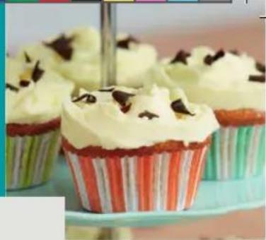 Close-up of three colorful striped cupcakes with cream and chocolate toppings on a green stand (no text or symbols visible)