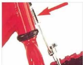 Close-up of red industrial pipe with a red arrow pointing to a component, showing text labels and symbols.