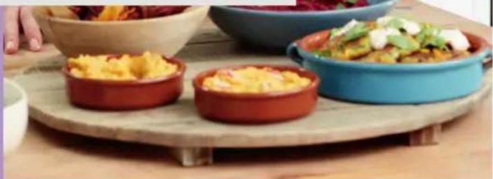 Three small food containers on a wooden tray, one containing scrambled eggs, another with sauce and garnish, and a third filled with vegetables (no visible text or symbols)