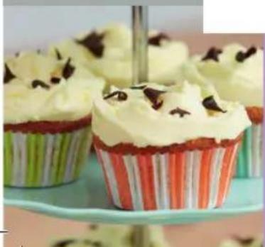 Close-up of cupcakes with white cream and chocolate toppings on a green stand (no text or symbols visible)