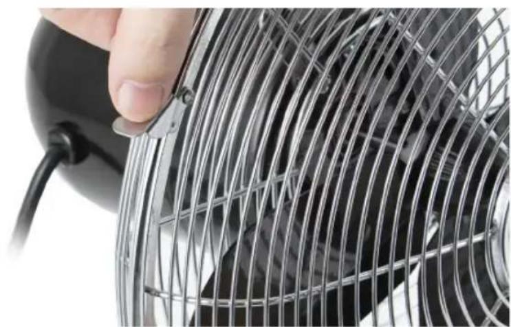 Close-up of a hand adjusting a metal wire mesh fan (no text or symbols visible)