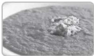 Close-up of a textured, granular surface with a small cluster of white specks (no text or symbols visible)