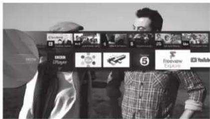 Black-and-white photo of two people holding a banner with logos and text including 'DISHI', 'LPlayer', '5', 'Freeview', and 'YouTube'.