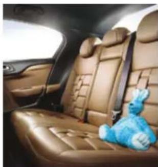 Interior view of a car showing leather back seats and a blue teddy bear resting on the side (no text or symbols visible)