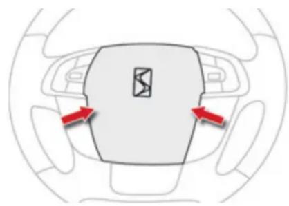Top-down view of a car's steering wheel and dashboard area with red directional arrows indicating clockwise motion (no text or symbols)