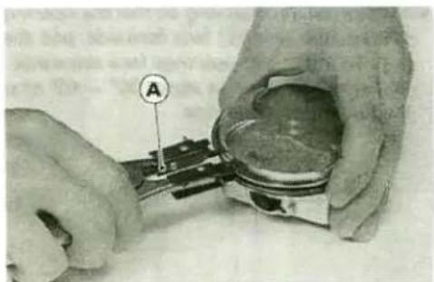 Close-up of hands assembling a mechanical component with a labeled section (A), no visible text or symbols beyond the label.