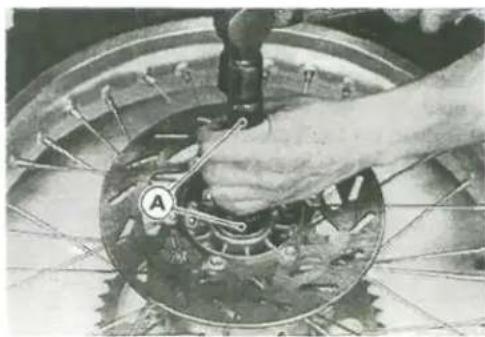 Close-up of a hand using a tool to adjust or install a mechanical gear component (no visible text or symbols)