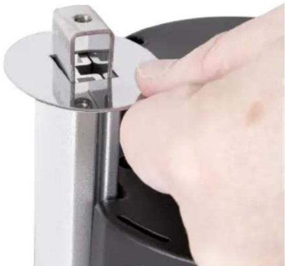 Close-up of a hand using a metal tool to cut a circular component (no text or symbols visible)