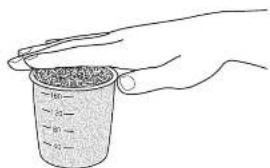 Hand holding a container filled with granular material, no text or symbols visible