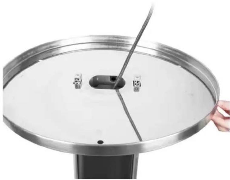 Close-up of a metallic circular fan or lid with a central connector and a hand holding the top edge (no text or symbols visible)