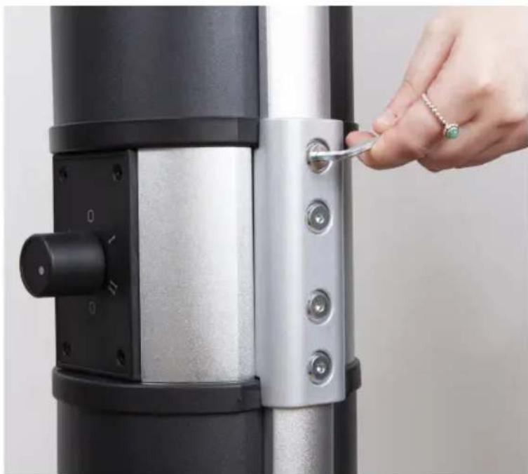 Close-up of a hand adjusting a metallic mechanical component with a small tool inserted (no visible text or symbols)