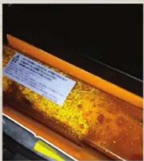 Close-up of a rusted metal surface with a blue label containing Chinese text, likely indicating a safety or inspection note.