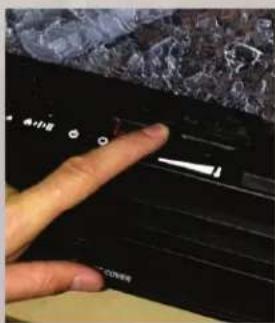 Close-up of a hand pressing a black control panel with Chinese text, showing a dark stone object above it.