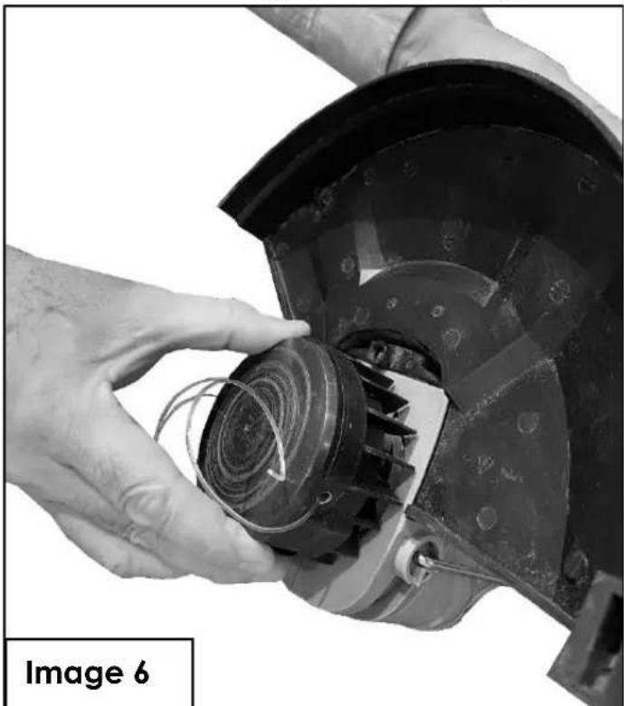 Close-up of hands operating a mechanical component with a coiled spring and housing (no visible text or symbols)