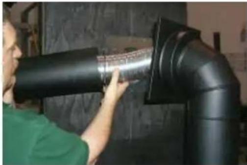 Person in green shirt applying black pipe to a black duct (no visible text or symbols)