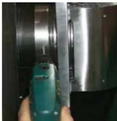 Close-up of a hand using a green power tool to press or install a metallic cylindrical component (no visible text or symbols)