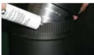 Close-up of a hand applying white adhesive to a black cylindrical container (no visible text or symbols)