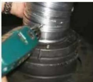 Close-up of a hand using a tool to cut a metallic cylindrical component (no visible text or symbols)