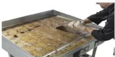 Person handling a tray with food on a metal tray (no visible text or symbols)