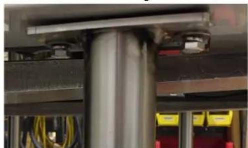 Close-up of a mechanical assembly with a metallic cylindrical component and yellow warning boxes (no visible text or symbols)