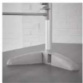 Close-up of a white plastic floor support structure with a vertical metal rod and curved base, against a tiled wall background (no text or symbols visible)