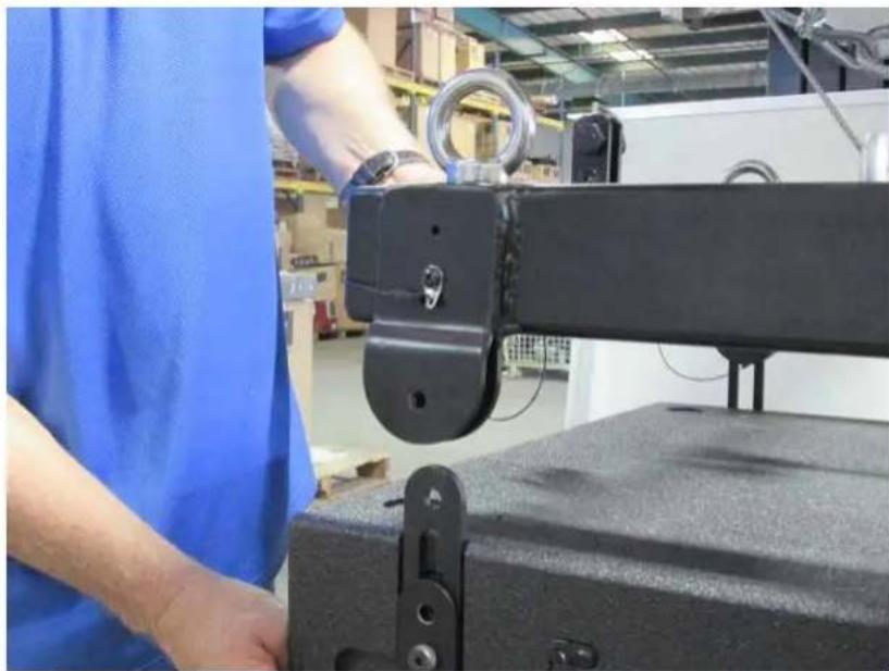 Factory worker in blue uniform adjusting a black mechanical bracket (no visible text or symbols)