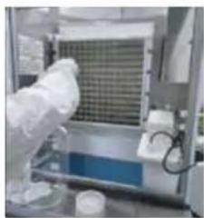 Laboratory setup with a gloved hand handling a blue liquid container (no visible text or symbols)