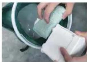 Person washing a green soap container into a white bucket (no text or symbols visible)