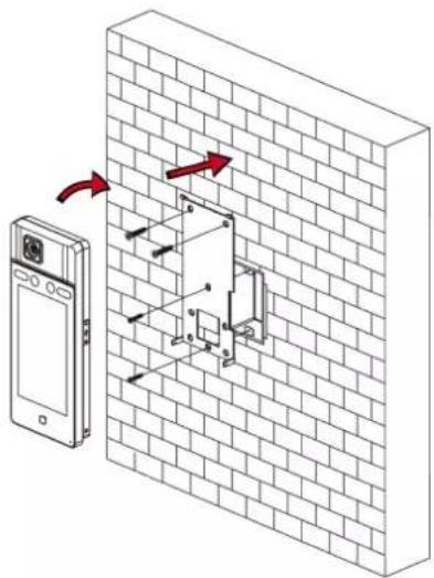 Diagram showing a device mounted on a brick wall with directional arrows indicating movement or force, likely illustrating a mechanical or electrical system.
