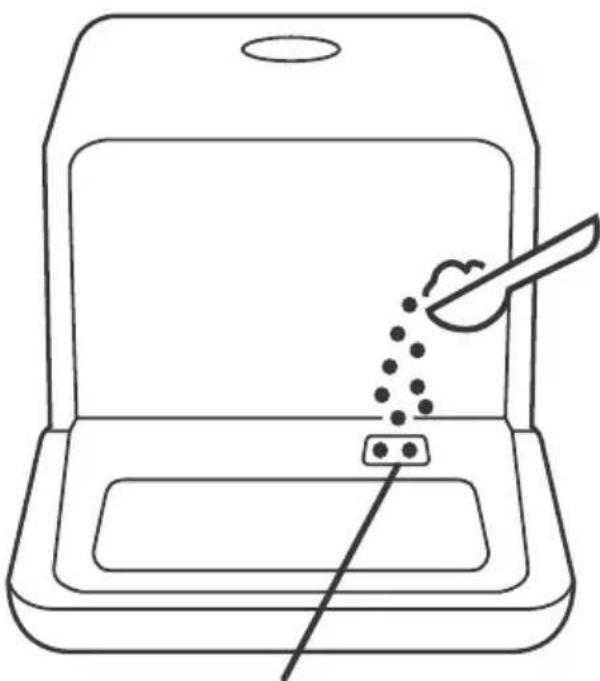 Line drawing of a device with a spoon and a tray, no text or symbols present.