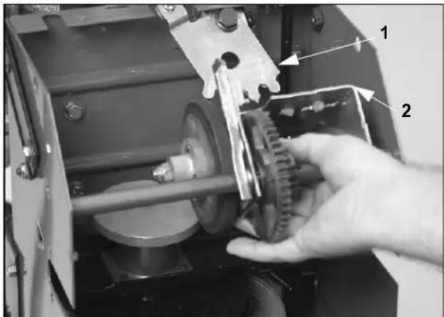 Close-up of a mechanical assembly with labeled parts, showing a hand holding a component labeled '1' and '2'.