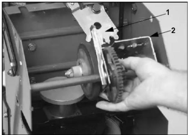 Close-up of a mechanical assembly with labeled parts, showing a hand holding a gear mechanism.