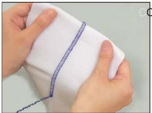 Close-up of hands holding a white fabric with a blue textured line drawn on it (no text or symbols visible)
