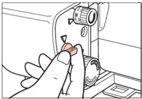 Hand operating a sewing machine needle to press a small knob (no text or symbols visible)