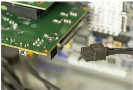 Close-up of a green printed circuit board with connector pins and connectors, partially connected by wires (no visible text or symbols)