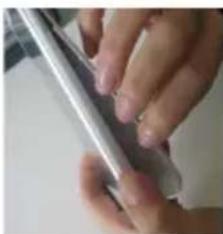 Close-up of a hand holding a metallic object, possibly a tablet or electronic device (no visible text or symbols)