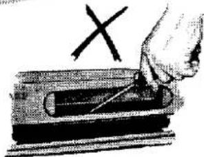 Illustration of a hand using a tool to cut a rectangular object with an 'X' mark above (no text or symbols on the object itself)