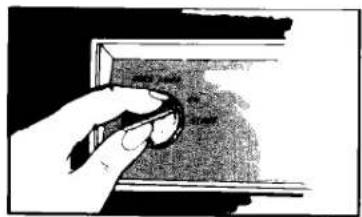 Hand holding a circular object with textured surface, possibly part of a device or tool (no visible text or symbols)