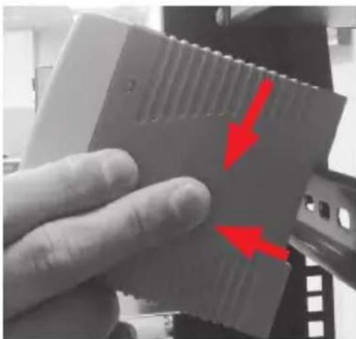 Close-up of a hand holding a computer RAM module with red arrows pointing to its side (no text or symbols visible)