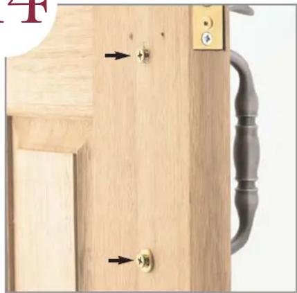 Close-up of a wooden door handle with two gold buttons and a black handle, showing part of a door panel (no text or symbols visible)